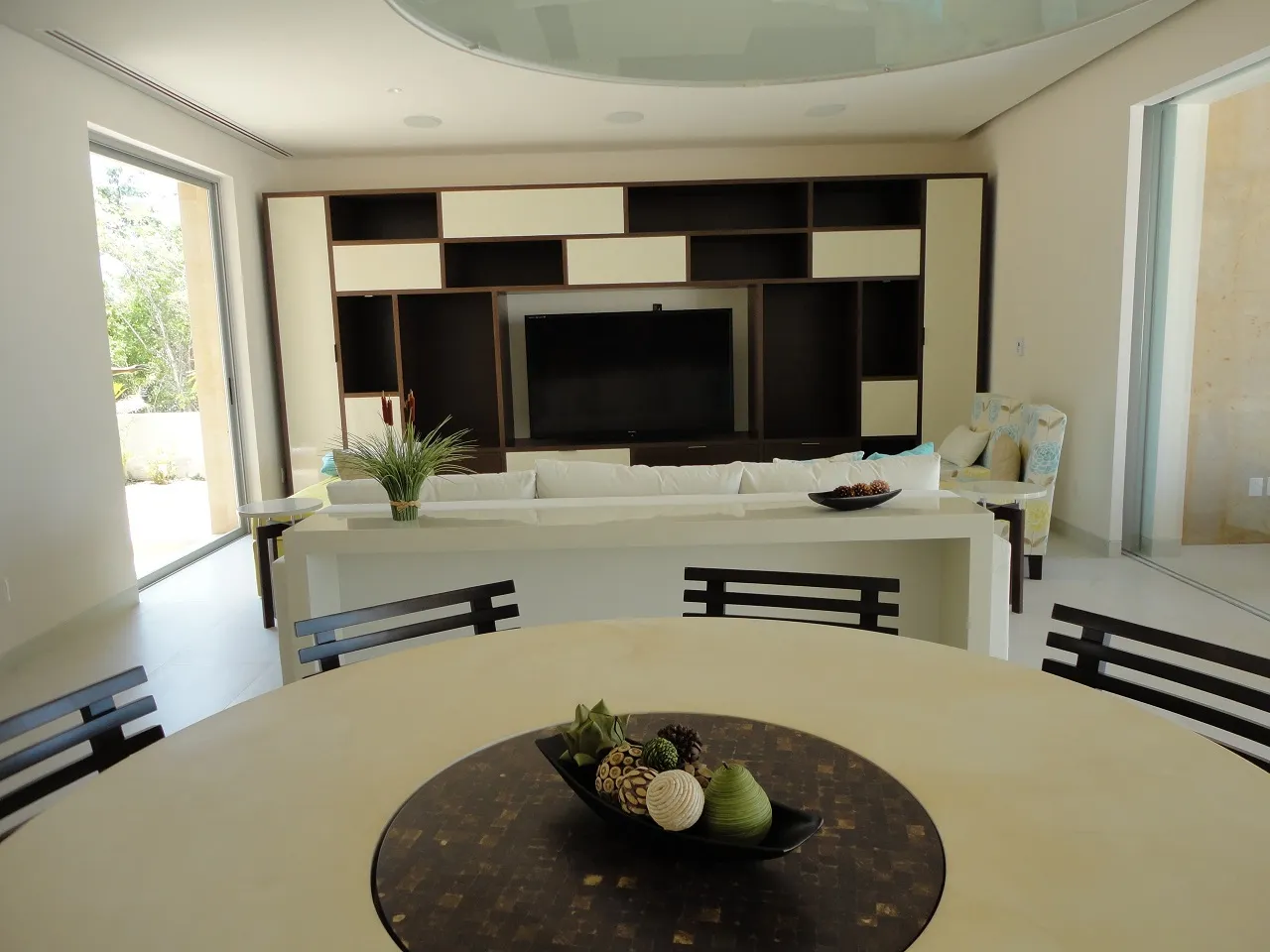 Sala con muro de entrepaños en blanco y negro, sofá claro y mesa redonda de comedor.