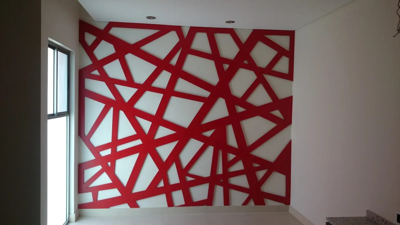 Muro con celosía de listones en rojo sobre fondo blanco, en una estancia con ventanal.